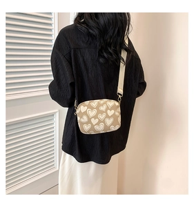 Detail view of beige PU crossbody bag with white heart prints and adjustable strap