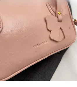 Close-up of light pink embossed PU leather handbag with a leather bow charm and logo
