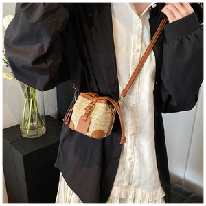Gros plan d'un mini sac seau en paille avec cordon en cuir et bandoulière marron