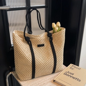Fashionable beige woven straw tote bag with black rope handles and spacious interior