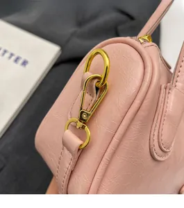 Detailed macro view of light pink textured leather bag with gold metal clasp hook