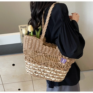 Détail du sac bandoulière en paille tressée avec motif crochet et breloque papillon
