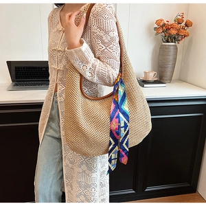 Detail of straw shoulder bag featuring brown leather strap and colorful silk scarf accent