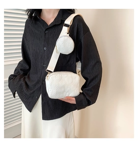 Detail of white PU leather crossbody bag with heart embossing and round coin purse