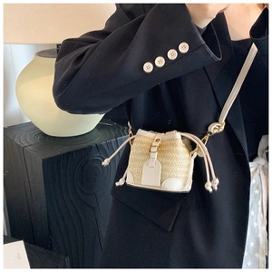 Chic straw and white leather crossbody bucket bag worn with a sophisticated blazer look