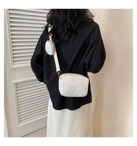 Rear view of a white heart-embossed crossbody bag with a small round coin purse on strap