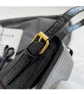 Detail of adjustable golden metal buckle and faux crocodile texture on black strap