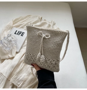 Nahaufnahme der cremefarbenen Häkeltasche mit gewebter Schleife und hohlen Blumenmustern