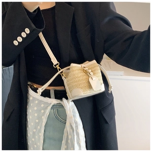 Detail view of the hand-woven straw bucket bag with cream leather trim and drawstring