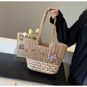 Détail du sac cabas en paille tissé à la main avec texture ajourée et fleur violette
