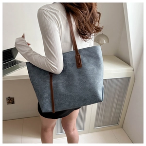Dettaglio trama della borsa tote in denim blu con manici in pelle marrone indossata