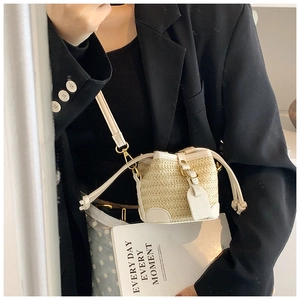 Detail of straw bucket bag with cream leather trim and adjustable crossbody strap