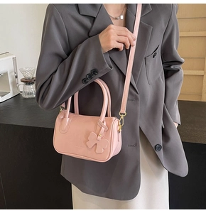 Close-up of pink shiny PU leather handbag with a bow charm and adjustable shoulder strap