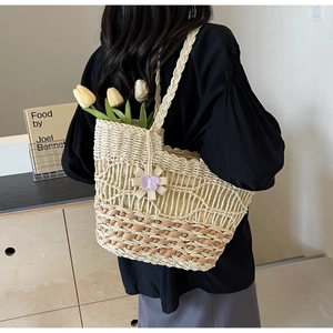 Détail d'un sac à main tendance en paille avec pendentif fleur violette en décor intérieur