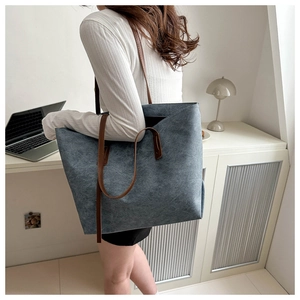 Borsa tote blu in feltro con manici in pelle marrone in un ufficio con un laptop