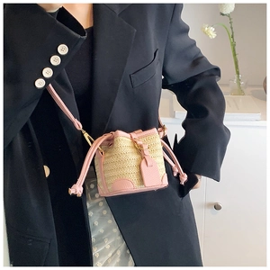 Detailed close-up of a pink leather and straw mini bucket bag worn by a model in a suit