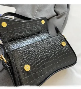 Detailed macro view of black crocodile pattern flap bag with golden magnetic snap buttons