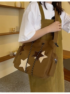 Detail of a brown canvas shoulder bag with star patches and drawstring closure