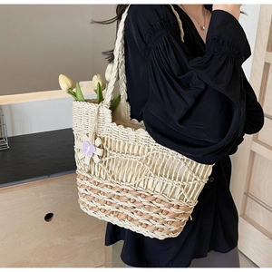 Détail du sac cabas en paille tissée avec breloque fleur mauve et texture beige et marron