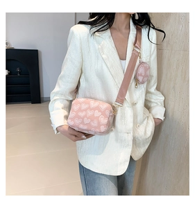 Close-up of pink heart-patterned crossbody bag with small round coin purse detail