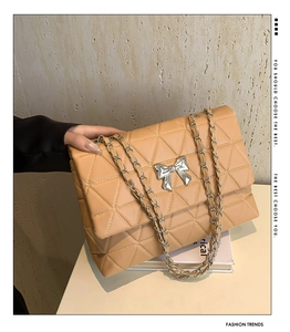 Gros plan sur le sac bandoulière beige matelassé en cuir PU avec nœud argenté et chaîne
