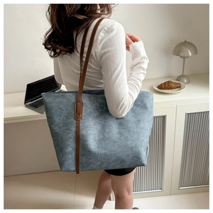 Borsa tote in denim blu con cinturini in pelle marrone in un ambiente da ufficio moderno
