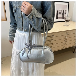 Detail of silver metallic handbag with checkered bow accent shown on female model