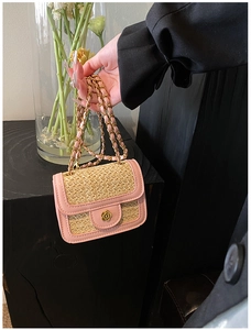 Dettaglio borsa in paglia intrecciata con finiture in pelle rosa e chiusura a camelia