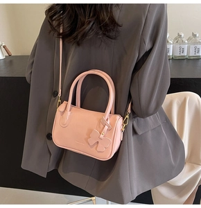 Detailed close-up of a pink PU leather crossbody bag worn with a gray blazer