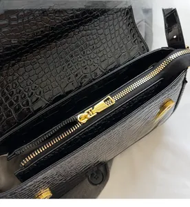 Detail of smooth gold zipper and crocodile texture on black crossbody square bag