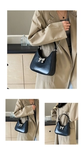Detail of black crescent handbag featuring silver bow hardware and chic chain strap
