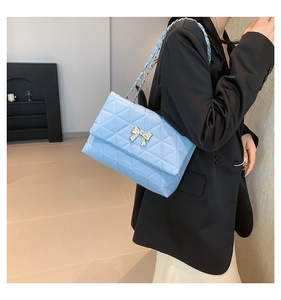 Détail du sac bandoulière matelassé bleu clair avec boucle nœud argenté et chaîne