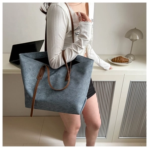 Vista dettagliata della borsa tote in denim grigio-blu con manici in pelle marrone