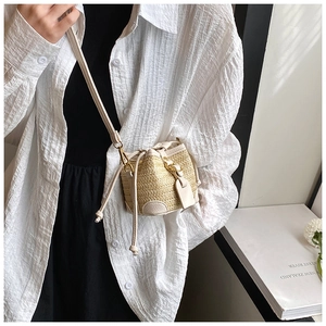 Detailed view of straw bucket bag with cream leather trim and gold metal hardware