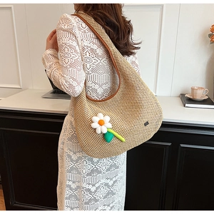 Detail of hand-woven straw hobo bag with large 3D daisy flower and brown leather trim