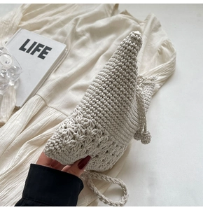 Detail eines hohl gewebten Blumenmusters an einer minimalistischen cremeweißen Stricktasche
