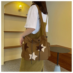 Detail of brown canvas crossbody bag with star patches and drawstring closure