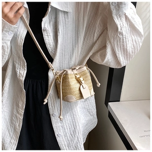 Close-up of a mini straw bucket bag with leather drawstring and adjustable strap