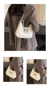 Close-up of cream crescent shoulder bag with silver bow detail and metal chain strap