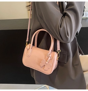 Detail view of pink PU leather handbag with elegant bow charm and fine double handles
