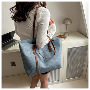 Dettaglio della borsa tote blu con trama unica e tracolle in pelle marrone in ufficio