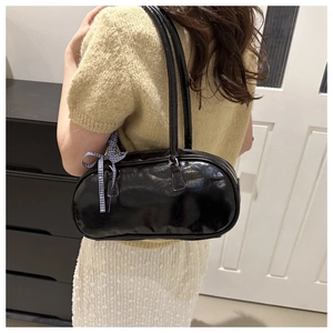 Detail of glossy black faux leather shoulder bag with chic checkered bow decoration