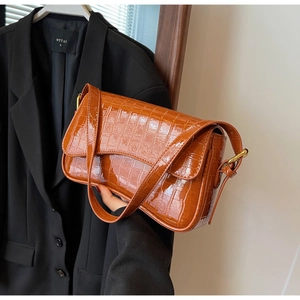 Detail of brown crocodile pattern glossy leather shoulder bag with gold hardware