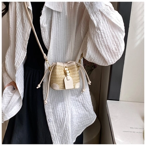 Detailed view of mini straw bucket bag with white leather trim and golden metal buckle