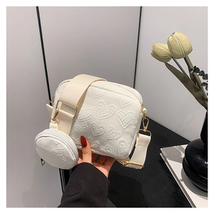 White PU crossbody bag with embossed heart pattern and a round mini coin purse detail