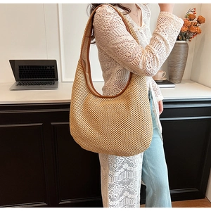 Close-up of the straw woven tote bag with brown leather straps and detailed texture