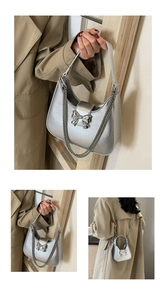 Detail of silver metallic hobo bag featuring a bow buckle and convertible chain strap