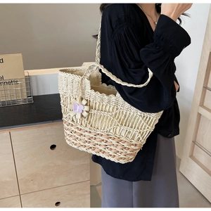 Détail du sac cabas en paille tissé main blanc crème avec base marron et breloque fleurie
