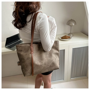 Grande borsa tote retrò marrone con spalline in pelle indossata in un interno minimalista