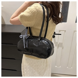 Close-up of black glossy PU leather shoulder bag featuring a blue plaid bow accessory